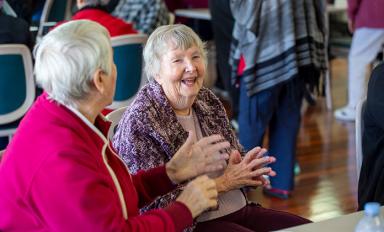 A photo of two older people communicating by sign language